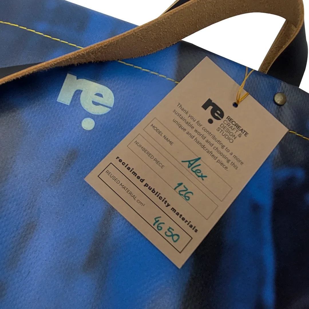 Handmade blue Alex bag from reclaimed advertising banner material, with leather handles and one interior pocket. Unique and numbered. - tag