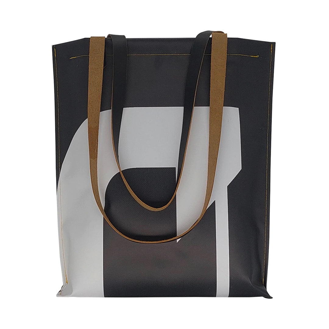 Handmade tote bag crafted from reclaimed banner material with leather handles and an interior pocket. A unique numbered piece made in Lisbon by ReCreate. - front