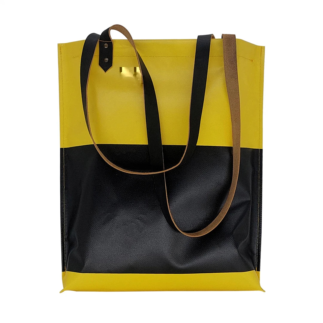 One-of-a-kind yellow and black handmade bag in reclaimed advertising banner, with leather handles and an inside pocket. Numbered ReCreate piece. - front