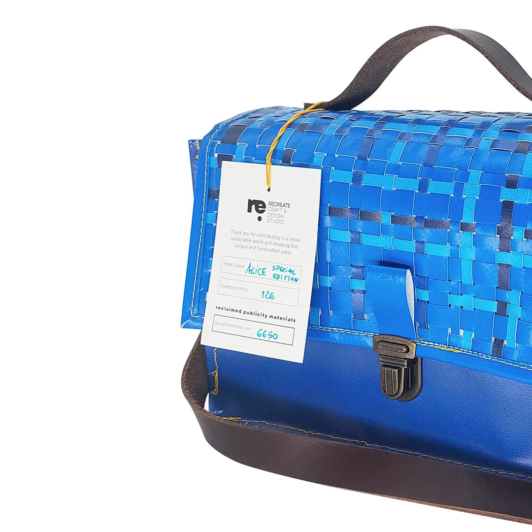 Alice Special Edition Bag 126 by ReCreate, a blue structured bag in reclaimed advertising banner with woven flap and leather strap. - tag