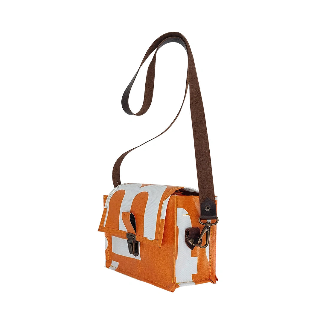 Anita Bag 424 by ReCreate, a compact orange bag in reclaimed advertising banner with bold white graphics, leather strap and metal clasp. - side