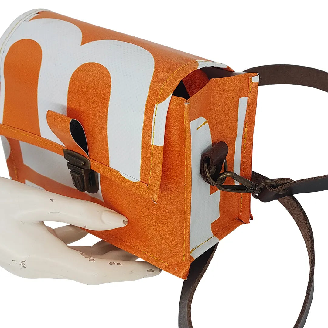 Anita Bag 424 by ReCreate, a compact orange bag in reclaimed advertising banner with bold white graphics, leather strap and metal clasp. - detail