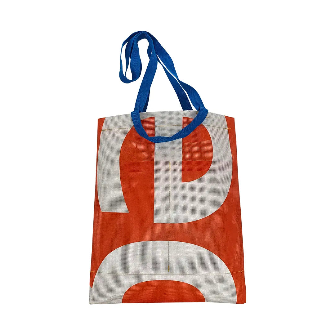 Red and white tote made from reclaimed advertising mesh banner, with blue handles and bold graphic curves from the original print. - back