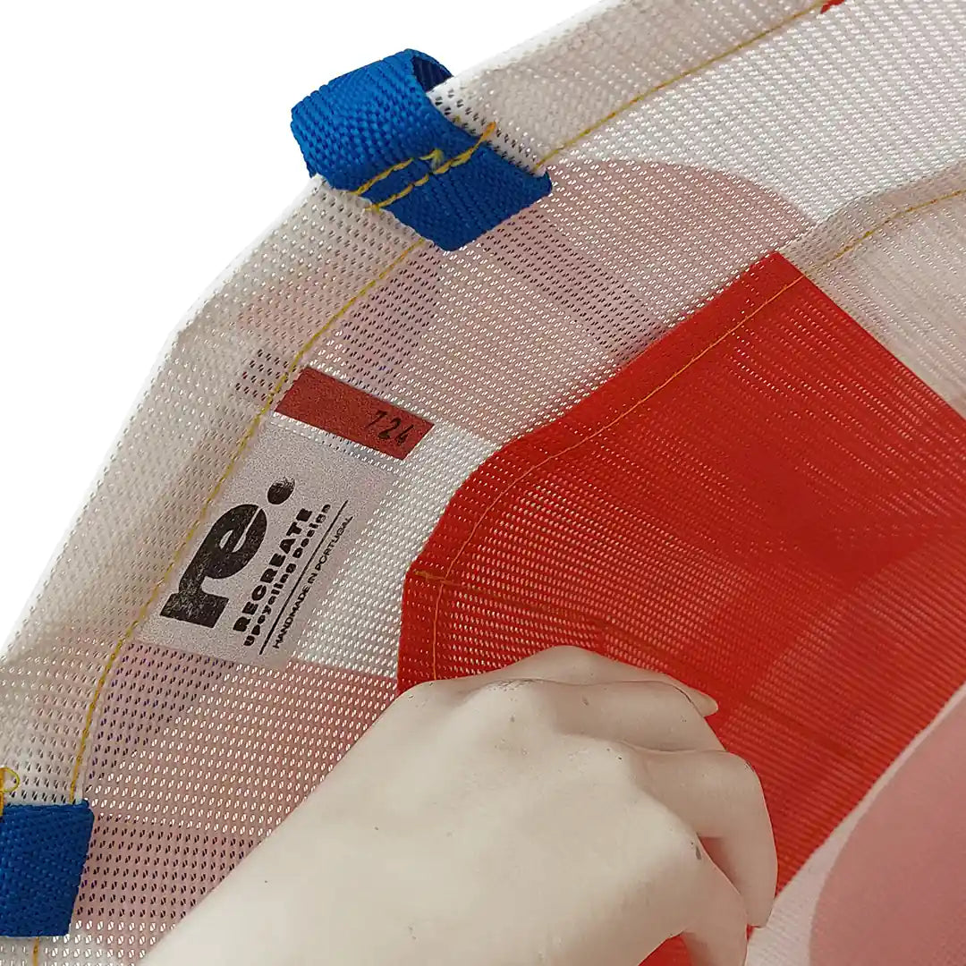 Red and white tote made from reclaimed advertising mesh banner, with blue handles and bold graphic curves from the original print. - pockets