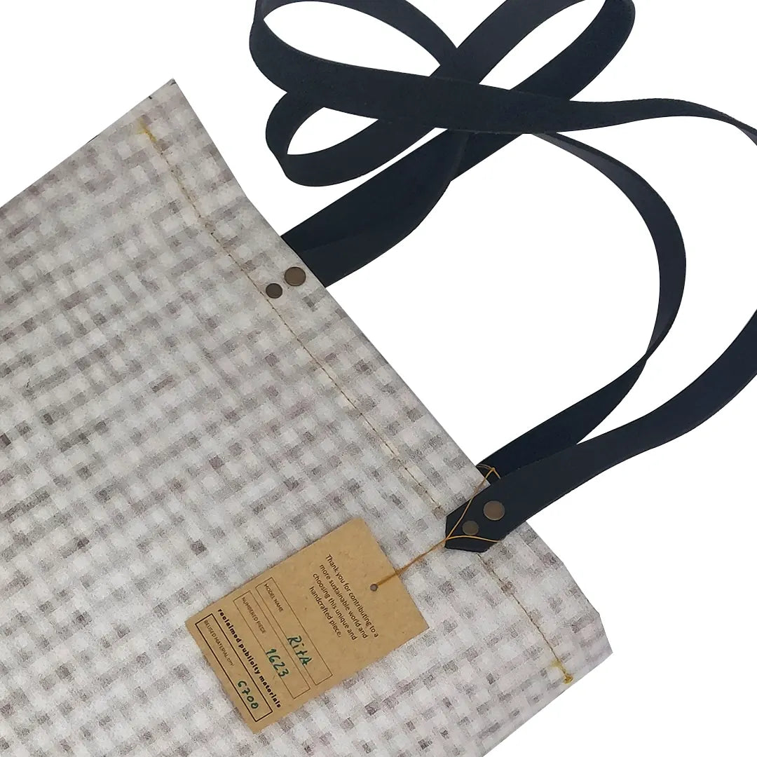 Rita Bag 1623 by ReCreate, a pale woven tote in reclaimed advertising banner with black leather straps and one inner pocket. - tag