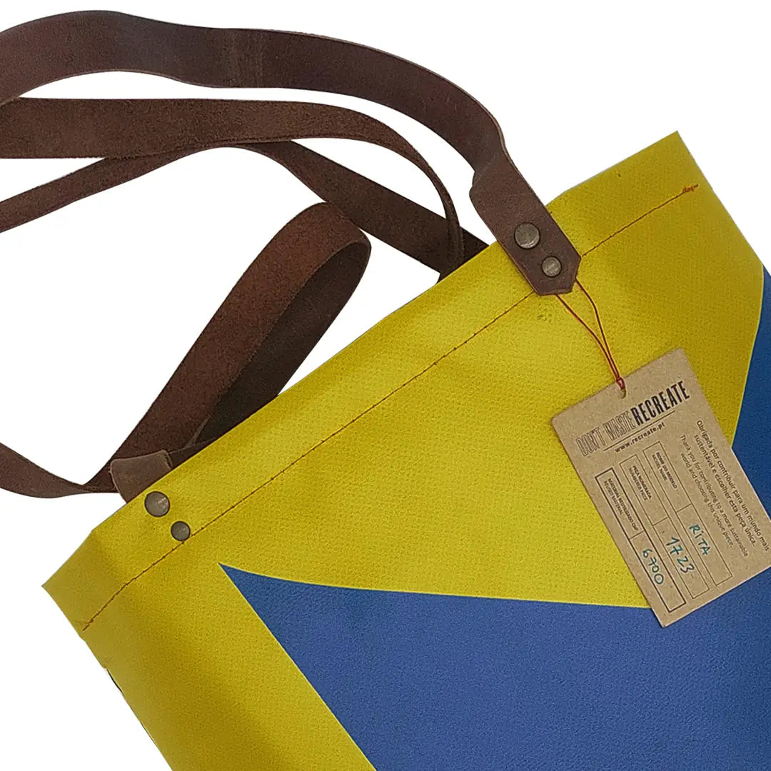 Rita Bag 1723 by ReCreate, a yellow and blue tote in reclaimed advertising banner with woven front, leather straps and one inner pocket. - tag