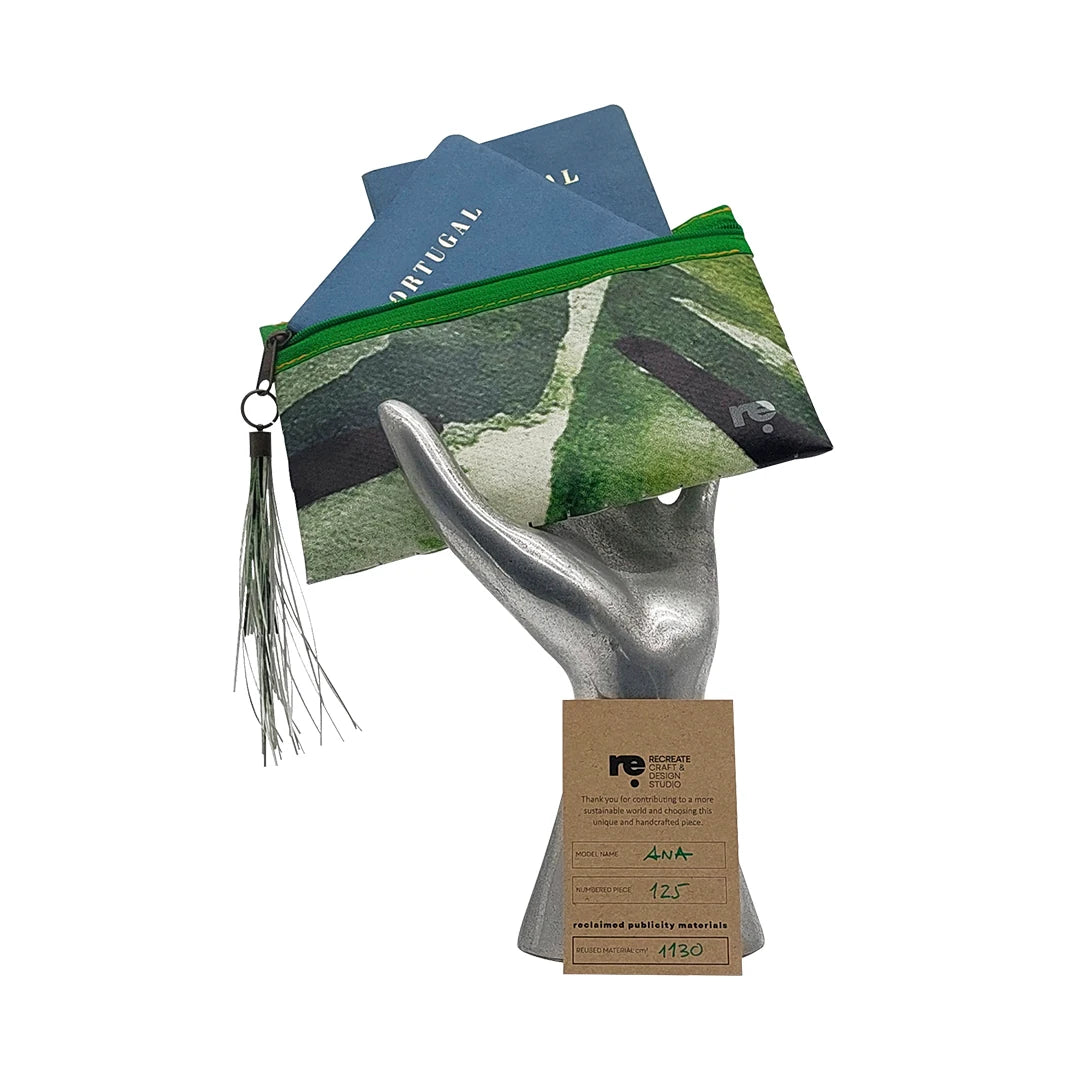 Green pouch made from reclaimed advertising banner, with woven texture, graphic fragments and a zip closure. A unique object by ReCreate. - on hans