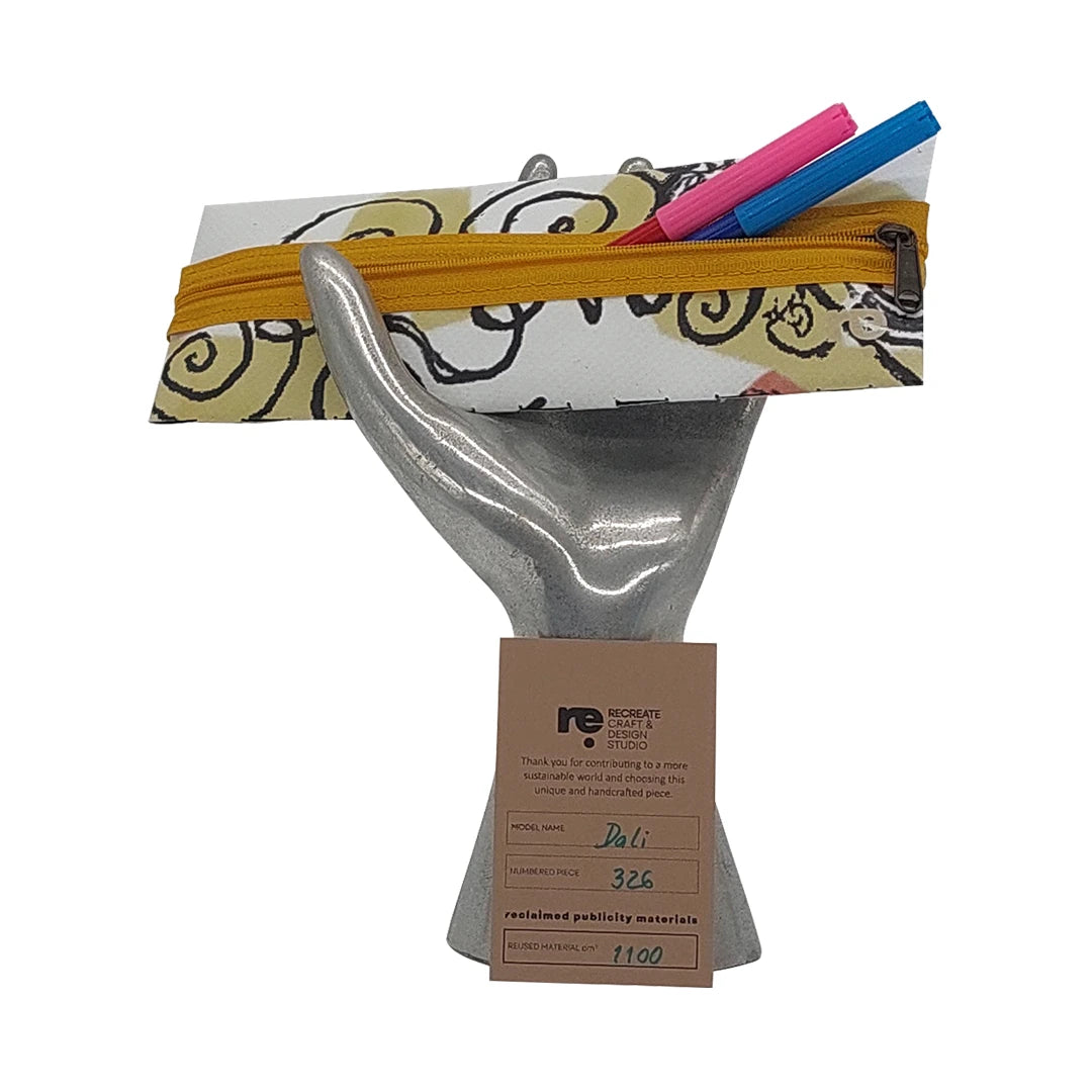 Slim zipped pouch made from reclaimed advertising material, ideal for pens, small objects and daily essentials. - on hand