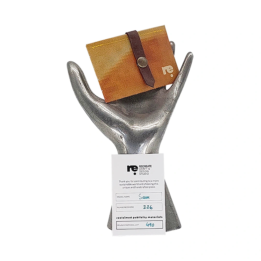 Sam Wallet 226 is a compact ReCreate wallet in reclaimed advertising banner, with warm ochre tones, woven detail and space for 6 cards. - on hand