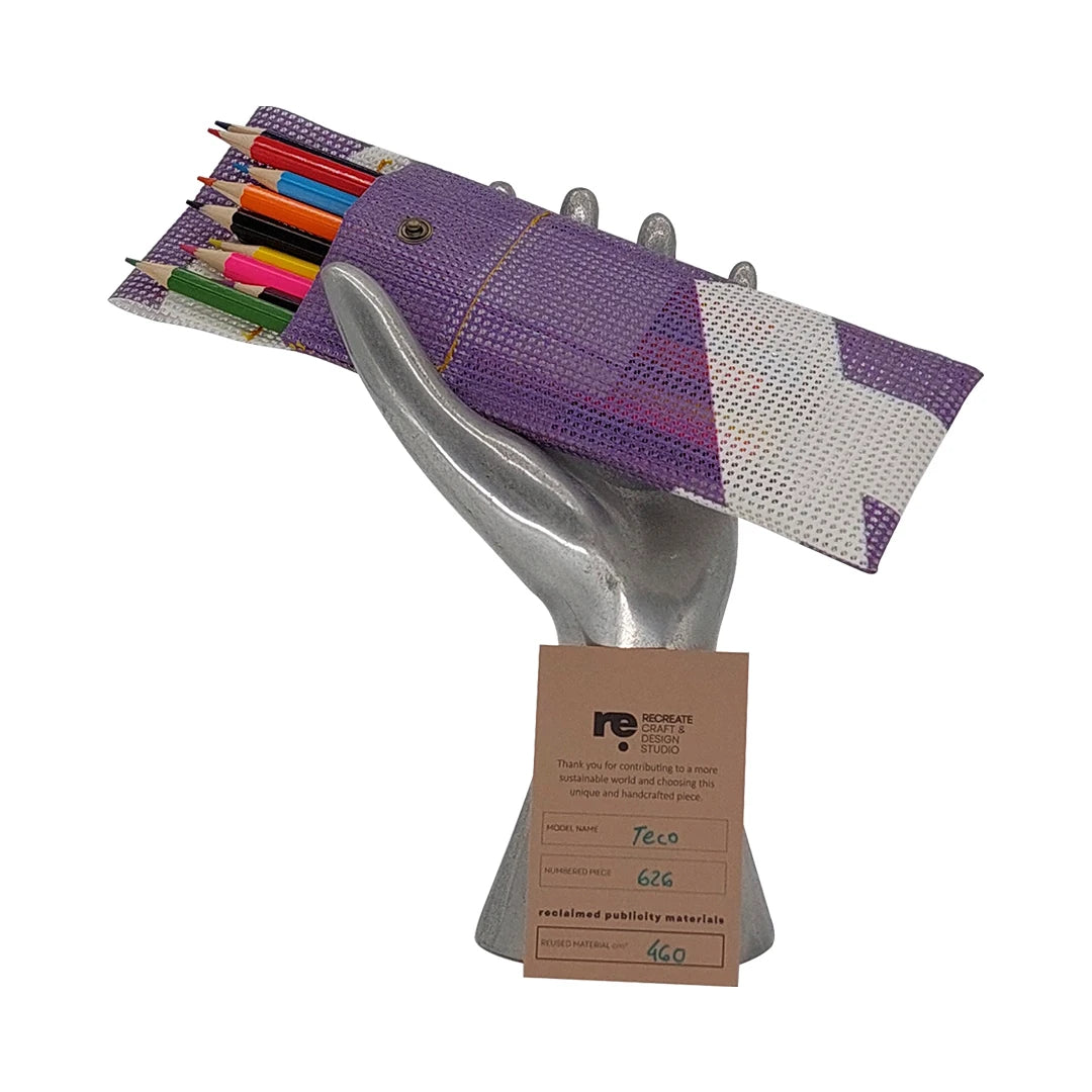 Compact pouch made from reclaimed micro-perforated banner, featuring a purple-and-white graphic surface and snap closure. - on hand