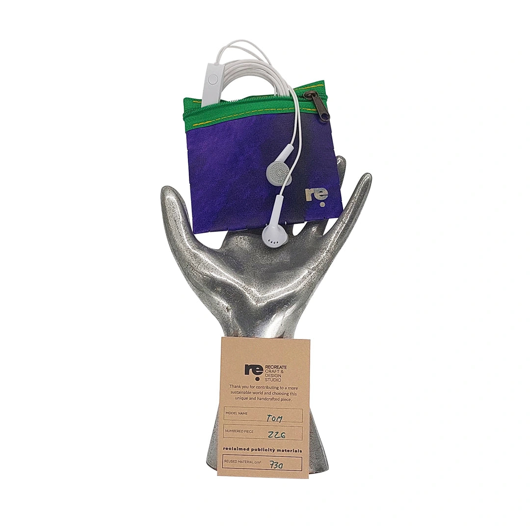 Tom Pouch 226 is a ReCreate pouch made from reclaimed advertising banner, with deep violet tones, green zip and woven back. - on hand