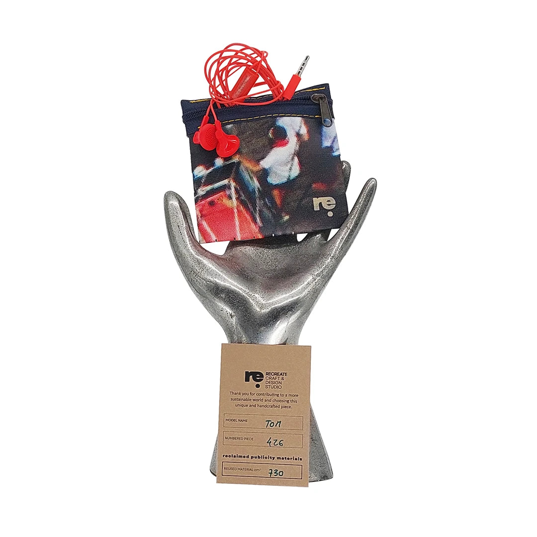Tom Pouch 426 is a ReCreate pouch made from reclaimed advertising banner, with dark photographic tones, red flashes and woven detail. - on hand